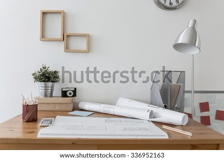 Messy desk with architect\'s plans on it