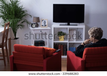 Pensive widow sitting alone in living room