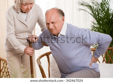Woman helping an elderly man having a back pain