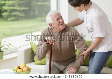 Young woman helping old man to stand up