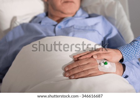 Close-up of caregiver holding his patient\'s hand to support