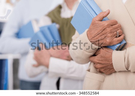Senior people holding books in blue cover