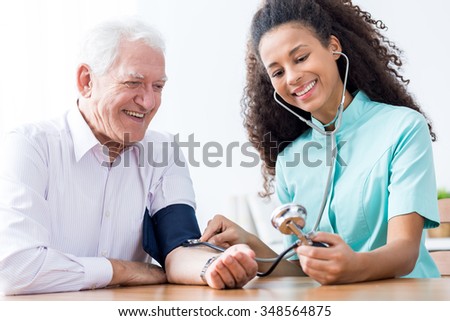 Smiling senior man having measured blood pressure