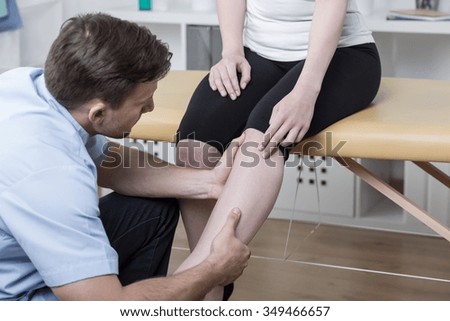 Young physiotherapist diagnosing patient with painful knee