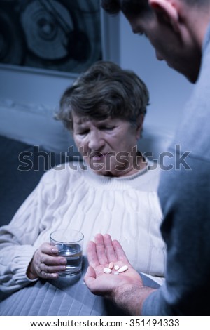 Image of male carer and elderly woman taking medicines