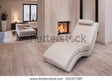 Photo of new design white leather armchair standing beside fireplace