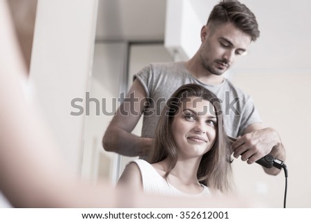 Hairdresser using hair straightener at hair salon