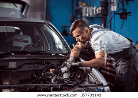 Young dirty mechanic working in car repair shop