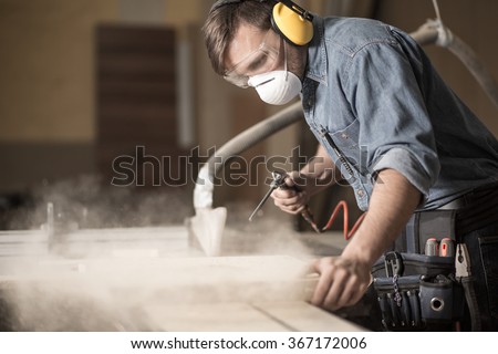Horizontal view of professionally dressed carpenter varnishing a board