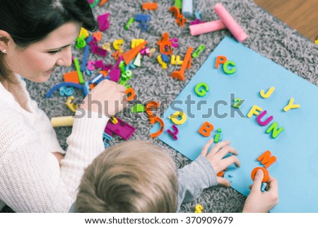 Boy during session with speech therapist learning letters