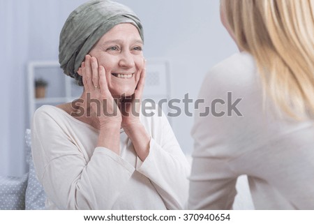 Smiling cancer woman with headscarf and young blonde girl