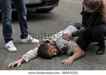 Woman checking if man hit by a car is alive