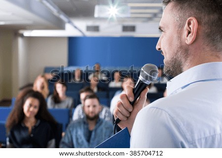 Close up of lecturer with microphone talking to group of students