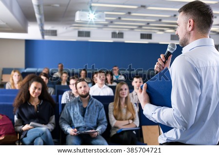 Young university teacher talking to group of students