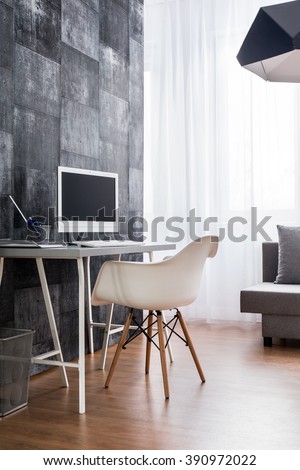 Home office with flooring, desk, chair, computer and decorative wallpaper.