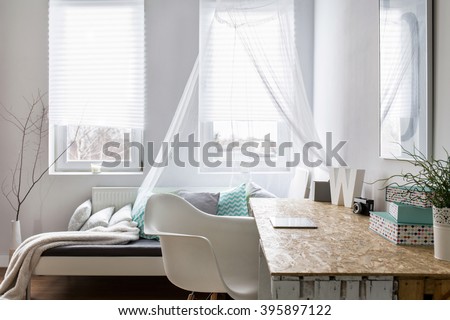 Small stylish room with couch next to the window and desk from hardwood