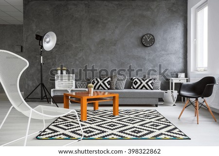 Grey interior with sofa, chairs, standing lamp, small wood table and black and white pattern decorative elements