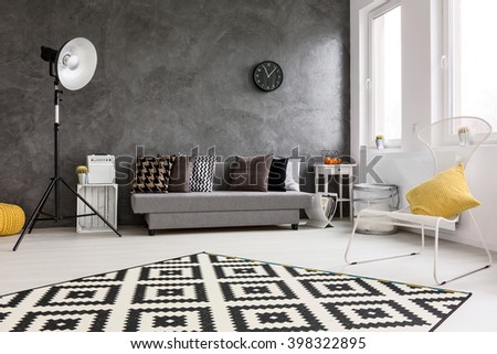 Spacious, grey living room with sofa, chair, modern standing lamp, small wood table and decorative carpet