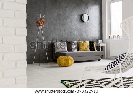 Modern, grey interior with sofa, chair, yellow details and stylish decorations