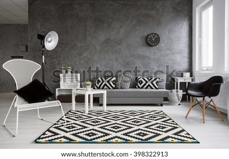 Grey living room with sofa, chairs, standing lamp, pattern carpet and trendy decorative details