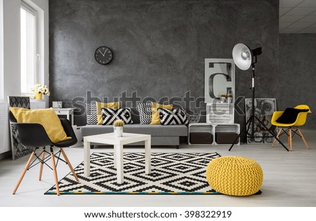 Spacious, grey living room with sofa, chairs, standing lamp, small coffee-table, decorations in yellow, black and white