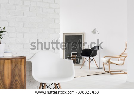 White interior with comfortable chairs, wood furniture and decorative brick wall