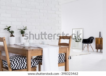 Spacious interior with wood table, chairs, mirror and decorative brick wall