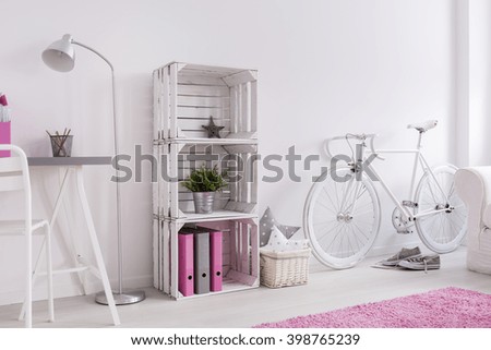Light room with desk, standing lamp, bookcase, bike and pink carpet