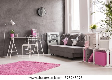 Spacious interior in grey, pink and white with desk, office, lamp, sofa and bookcase