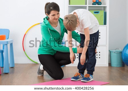 Physiotherapist and boy exercising in rehabilitation center.