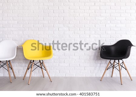 New chairs in white, yellow and black standing in white room with brick wall