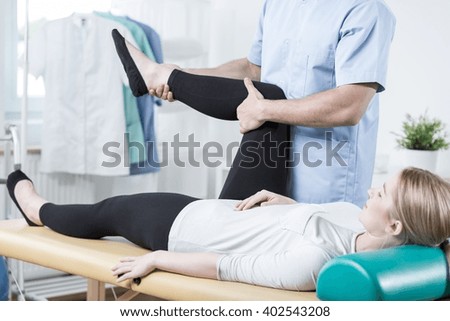 Male chiropractor stretching female leg during rehabilitation