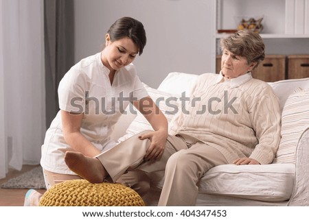 Older woman with painful knee and helpful carer