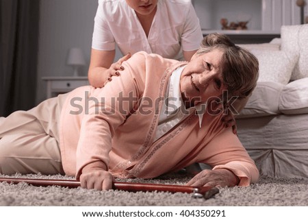 Disabled older woman on floor and caring young assistant