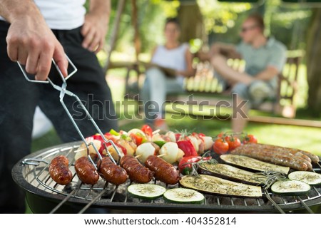 Grilling sausages and vegetables on bbq party