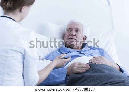 Shot of a senior man laying on a hospital bed and answering to his doctor\'s questions
