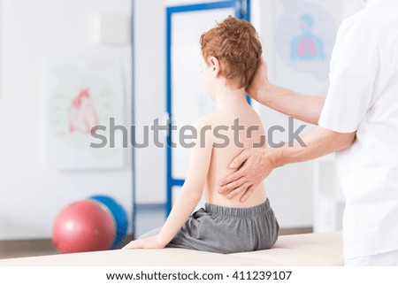 Little boy with scoliosis in rehabilitation clinic. Physiotherapist working with special method on boy\'s spinal column