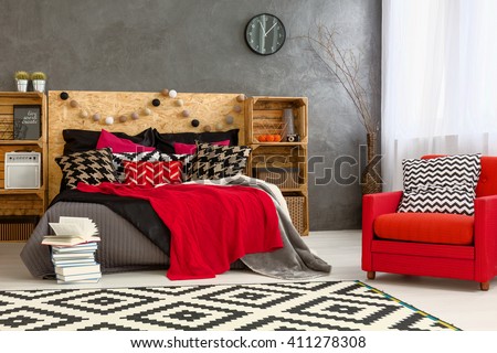 Bedroom with big bed, DIY furniture, pattern carpet and red armchair