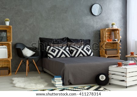 Spacious bedroom in grey, with handmade, wood furniture, big bed and decorative, pattern pillows