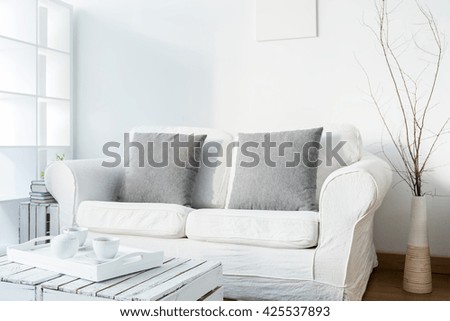 Spacious white living room in scandinavian style with coffee table made of old boxes. On coffee table fresh coffee on tray