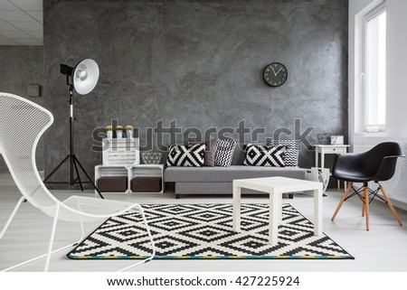 Spacious living room decorated with style. Grey walls, white wooden floor and white and black decorations