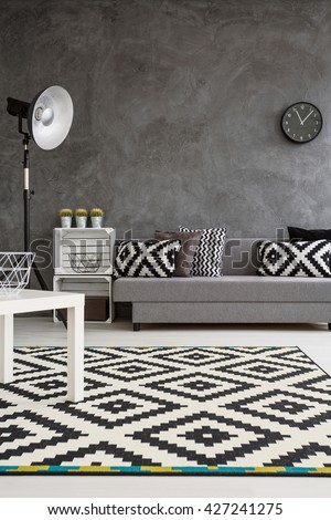 Modern decor of living room with grey walls and black and white carpet on wooden floor