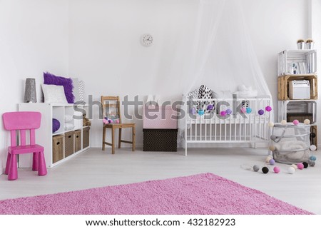 Cute pink and white bedroom designed for little baby girl. By the wall cradle and shelf. On the floor pink carpet