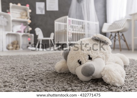 Shot of a teddy bear laying on a carpet in a cozy baby girl room