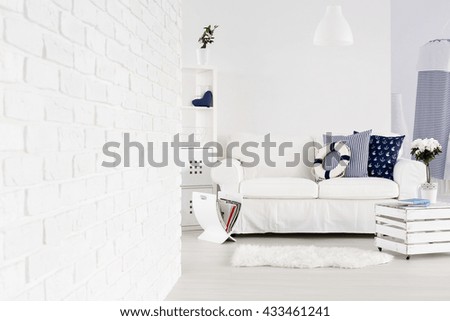 White spacious living room with brick wall, sofa and decorations in marine style