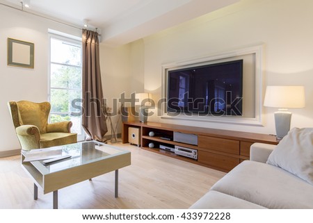 Stylish living room with comfortable armchair, small table, sofa and big tv