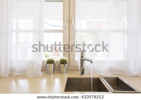 Close up of a kitchen sink, worktop, and window