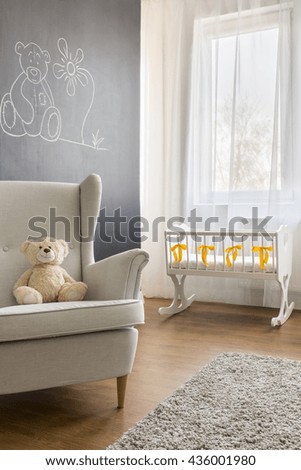 Cropped picture of an armchair and a crib in a modern nursery