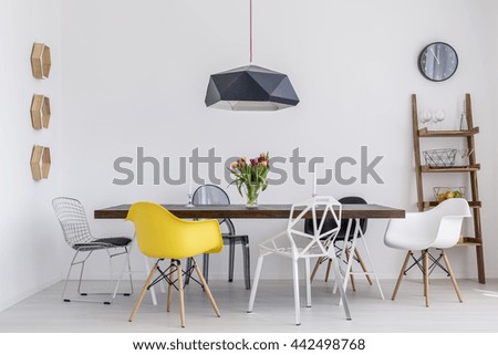 Shot of a creative dining room with a big table and six different chairs