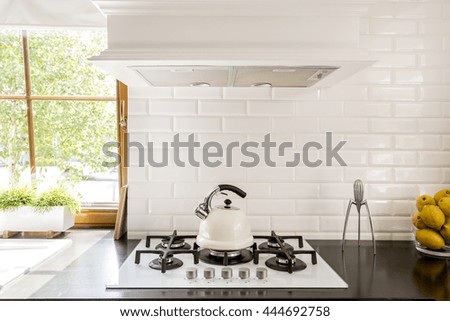 New style kitchen with dark worktop, white gas cooker and decorative brick backsplash